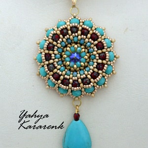 May include: A gold chain necklace with a turquoise and gold beaded pendant. The pendant features a round, multi-colored beaded design with a turquoise stone drop.