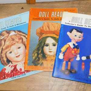 May include: Three vintage "Doll Reader" magazines. The covers feature images of antique dolls and Pinocchio. The magazines are in shades of blue, orange, and white, with text that reads "Collector's Guide To Dolls & Miniatures."