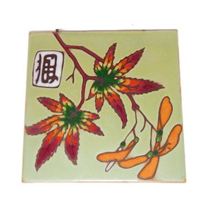 May include: A green ceramic tile with a painted design of a maple leaf branch with orange, red, and green leaves. The tile also features a white square with the Chinese character "福" (fú) meaning "good fortune" or "happiness".