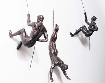 Grote x3 klimmende mannen met spijkerdoppen bronskleur abseilen hangend aan draadornamenten beeldjes muurhangende standbeelden bergbeklimmers kunst aan de muur