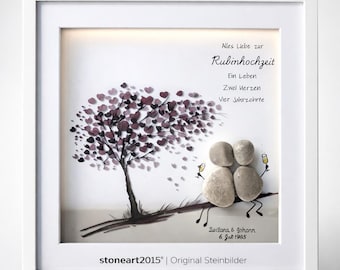 May include: A framed artwork featuring a tree with heart-shaped leaves in shades of purple. Two pebble figures sit beneath the tree, holding champagne glasses. Text in German reads "Alles Liebe zur Rubinhochzeit". The artwork is signed "stoneart2015".
