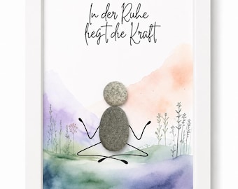 Puede incluir: Una obra de arte enmarcada que presenta una figura de piedra en una pose de meditación sentada. La figura está compuesta por dos piedras grises sobre un fondo de acuarela de colinas y plantas. El texto In der Ruhe liegt die Kraft está impreso.