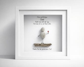 May include: White framed artwork with a pebble art figure holding a wine glass. The artwork includes German text that reads "A great boss, you don't find every day. Good that I had so much luck. Thank you for the time together!"