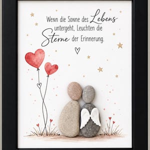 Könnte beinhalten: Ein gerahmtes Wandbild mit zwei Kieselsteinfiguren, eine davon mit weißen Engelsflügeln, stehend zwischen gemaltem Gras und roten Herzballons. Der Text lautet: Wenn die Sonne des Lebens untergeht, Leuchten die Sterne der Erinnerung.