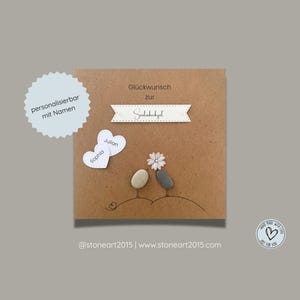 May include: A square brown card featuring the text "Glückwunsch zur Seidenhochzeit" on a banner, two pebble birds, a white flower, and two white heart-shaped cutouts labeled "Sophia" and "Julian". A circular sticker reads "personalisierbar mit Namen".