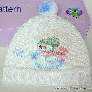 May include: White knitted hat with a snowman design in blue, pink, and green. The hat has a white pom-pom on top and the word "pattern" is written in blue on a purple background.