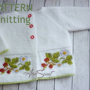 May include: White knitted baby cardigan with green trim and a strawberry and flower embroidery design. The cardigan has three red buttons.
