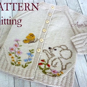 May include: A knitted cardigan in a cream color with a button closure. The cardigan features a whimsical embroidered design of an elephant, butterfly, and flowers. The text "Ana Sweet" is embroidered on the right sleeve.