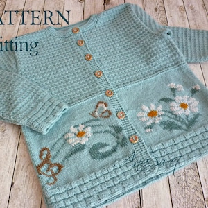 Könnte beinhalten: Ein hellblauer Strickcardigan mit einem Gänseblümchenmuster und braunen Knöpfen. Der Cardigan hat eine gerippte Struktur und eine leicht verkürzte Länge.