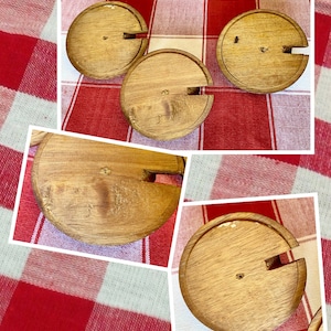 K&ouml;nnte beinhalten: Ein Satz von vier Weinflaschenverschl&uuml;ssen aus Holz. Jeder Verschluss ist kreisf&ouml;rmig mit einem Schlitz f&uuml;r den Korken und einem kleinen Holzstift. Die Verschl&uuml;sse sind aus hellfarbigem Holz gefertigt und auf einer rot-wei&szlig; karierten Tischdecke angeordnet.