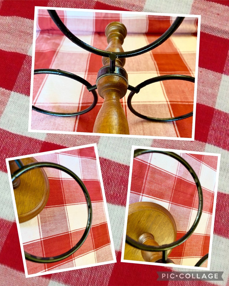 K&ouml;nnte beinhalten: Ein Weinhalter aus Holz mit einem Design aus dunklen Metallringen. Der Halter hat eine hellbraune Oberfl&auml;che und ist f&uuml;r mehrere Flaschen ausgelegt. Der Hintergrund ist ein rot-wei&szlig; kariertes Muster.