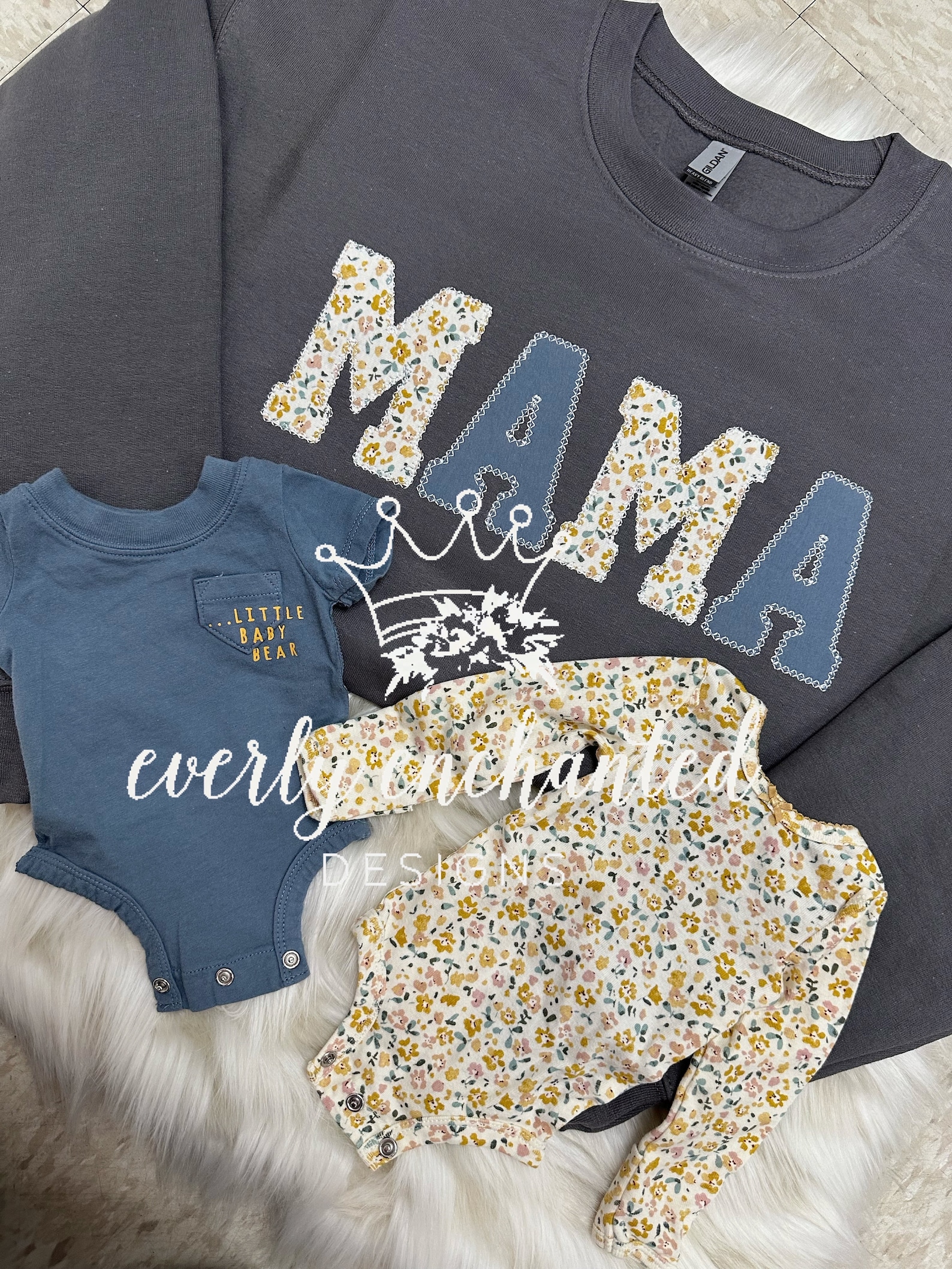 A blue sweatshirt that says mama with two baby onesies in front of it.
