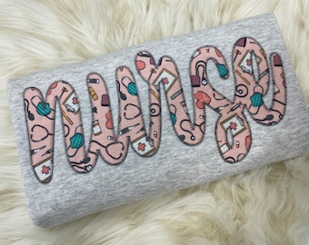 看護師の刺繍入りアップリケ スウェットシャツ | シンプルな看護用プルオーバー、医療現場へのギフト、パーソナライズされた RN シャツ クルーネック