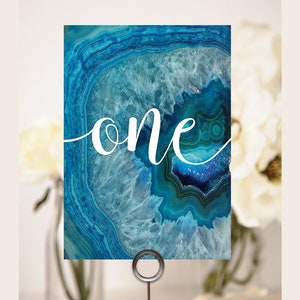May include: Blue agate table number card with the word "one" in white script.