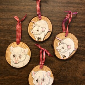 May include: Four white rat ornaments painted on wood slices with red and white gingham ribbon.