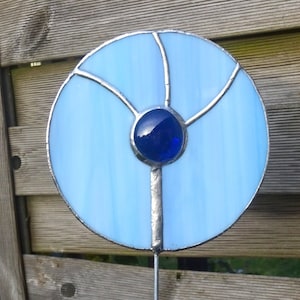 Könnte beinhalten: Ein blauer und silberner Bleiglas-Sonnenfänger mit einem dunkelblauen Zentrum. Der Sonnenfänger ist auf einem Metallstab.
