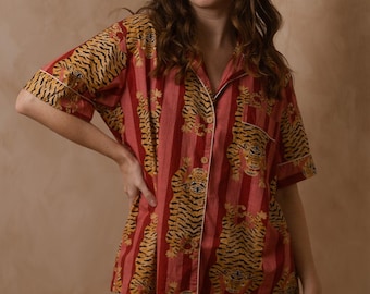 May include: A red and yellow striped pajama set with a tiger print. The set includes a short-sleeved shirt with a button-up collar and matching shorts.