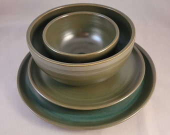 May include: A set of three green ceramic bowls, with a smaller bowl nested inside a larger bowl, and both bowls sitting on a matching green plate.