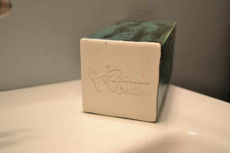 May include: A white ceramic rectangular box with a teal glaze and a signature that reads "Robin Creations".