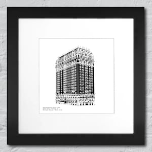 May include: Black and white architectural print of The Drake Hotel in Chicago, Illinois, framed in a black wooden frame. The print features detailed line art of the building's facade, with text at the bottom. The artwork is matted with a white border.
