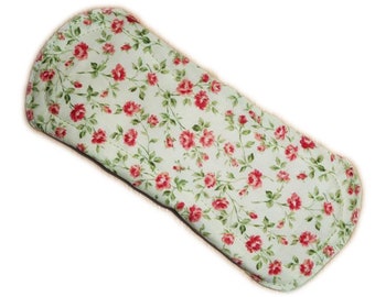 May include: A white cloth pad with a floral pattern of small red roses on green stems. The pad is rectangular with rounded edges.