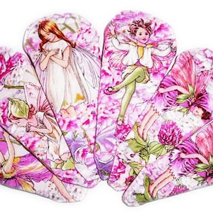May include: Set of seven pink and white hair clips featuring fairies and flowers. Each clip has a different fairy design with pink and white wings and a floral background.