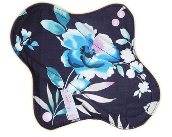 May include: A dark blue reusable cloth pad with a floral print featuring blue, white, and pink flowers. The pad has a snap closure and the text "Missie B" is visible on the pad.