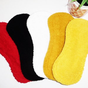 May include: Five reusable cloth menstrual pads in different colors: red, black, white, mustard yellow, and bright yellow. The pads are made of a soft, absorbent material.