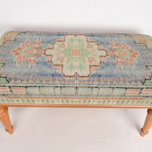 May include: A wooden bench with a colorful patterned cushion. The cushion has a blue, green, and orange geometric design.