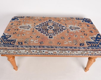 May include: A wooden bench with a patterned rug top. The rug is a traditional design with blue, red, and white colors.