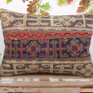 May include: Rectangular decorative pillow with a vintage, distressed look. The pillow features a central band of red and blue geometric patterns, framed by brown and tan patterned borders. A unique home decor item.