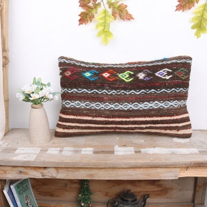 May include: A brown and beige patterned throw pillow with colorful geometric designs. The pillow is sitting on a wooden table.