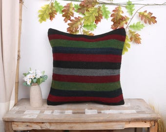 May include: A striped throw pillow with black, red, green, and gray stripes. The pillow is made of a soft, woven fabric and has a square shape.