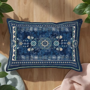May include: A rectangular throw pillow featuring a deep blue base with a distressed, weathered texture. The design includes a central circular medallion, symmetrical floral motifs, and intricate geometric borders in shades of cream and green.