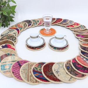 May include: A set of 20 colorful round woven coasters with a variety of patterns. The coasters are arranged in a circle around two white teacups and saucers.