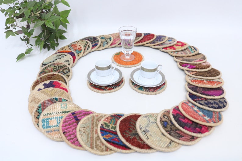 May include: A set of 20 colorful round woven coasters with a variety of patterns. The coasters are arranged in a circle around two white teacups and saucers.