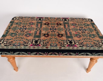 Puede incluir: Un banco de madera con un cojín estampado. El cojín tiene un diseño geométrico en tonos rojos, verdes, azules y negros sobre un fondo beige.