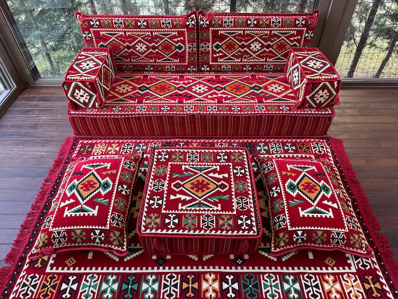 May include: A red and green patterned floor cushion set with a sofa, two square cushions, and a rectangular cushion. The cushions are all decorated with intricate geometric designs.