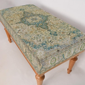 May include: A wooden bench with a patterned fabric cushion. The cushion features a floral design in shades of green, blue, and beige.