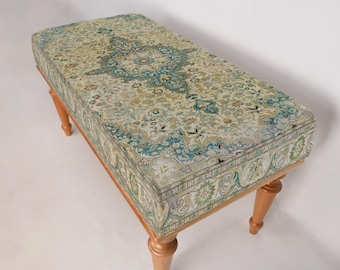 May include: A wooden bench with a patterned fabric cushion. The cushion features a floral design in shades of green, blue, and beige.