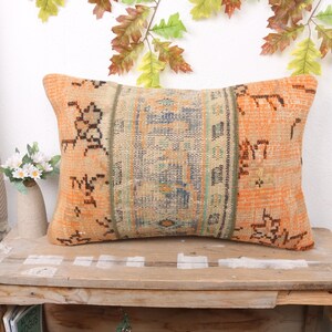 May include: A rectangular orange and cream throw pillow with a geometric pattern. The pillow is made from a woven fabric and has a fringed edge.