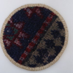 May include: A round, woven coaster with a colorful, geometric pattern in shades of red, blue, and green. The coaster has a natural, beige-colored border.