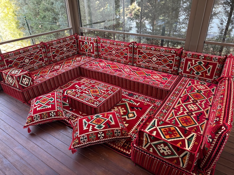 May include: A red and white patterned floor seating set with cushions and a coffee table. The set is made of fabric and has a traditional design.