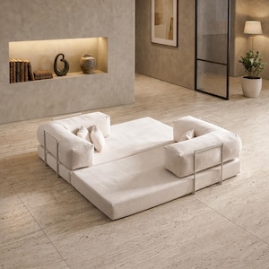 May include: Modern modular sofa in a neutral color palette. The sofa features a low profile design with a rectangular base and two L-shaped seating sections. The sofa is accented with metal frames and includes several throw pillows. The room has a minimalist design.
