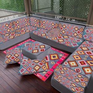 May include: A grey sectional sofa with a vibrant geometric pattern, accompanied by matching cushions and a rug. The sofa is 330 cm long and 190 cm wide. The rug is 70 cm wide.