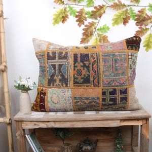May include: A rectangular throw pillow with a patchwork design featuring various shades of brown, red, and blue. The pillow is made of woven fabric and has a fringed edge.
