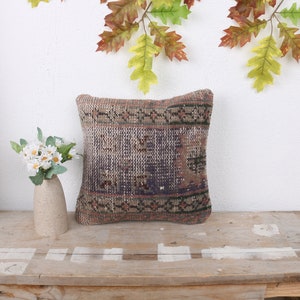 May include: A decorative throw pillow with a brown, beige, and blue patterned design. The pillow is made of woven fabric and has a fringed edge.