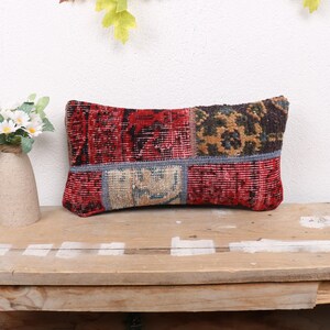 May include: A red, blue, and brown patchwork pillow with a geometric pattern. The pillow is sitting on a wooden table.