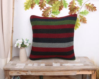 May include: A striped throw pillow with red, black, green, and gray stripes. The pillow is made of a soft, woven fabric and has a square shape.