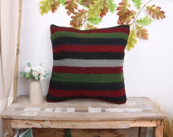 May include: A striped throw pillow with red, green, black, and gray stripes. The pillow is made of a soft, woven fabric and has a slightly textured surface.